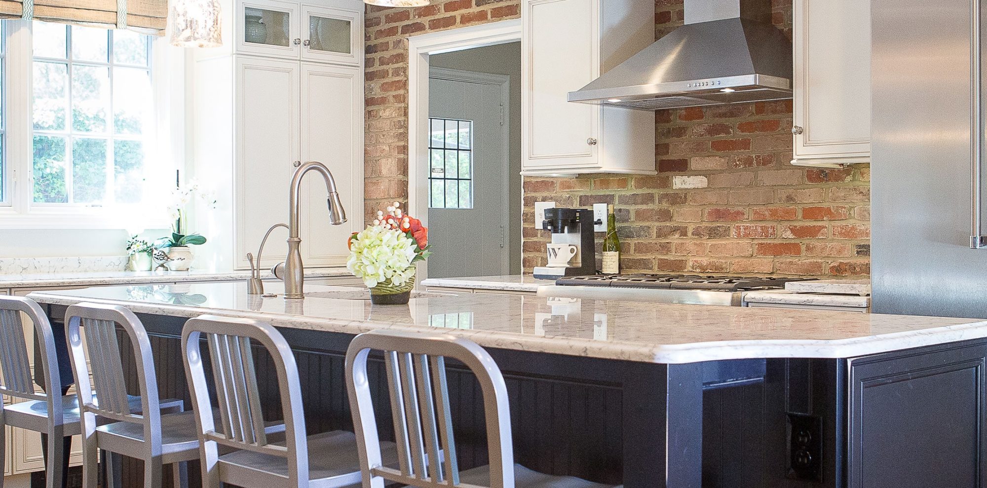 Warm marble counter tops meet brick wall in renovated kitchen